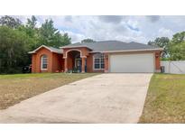 Charming single-story home with a two-car garage, arched entryway, and a spacious concrete driveway at 3234 Morven Dr, Spring Hill, FL 34609