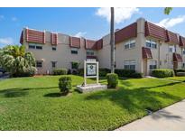 Attractive condo with a red tile roof, manicured lawn and tropical landscaping and signage at 10038 62Nd N Ter # 17, St Petersburg, FL 33708