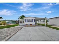 Charming single-story home with blue trim, carport, landscaped front, and paved driveway at 104 E Saint Johns Way, Apollo Beach, FL 33572
