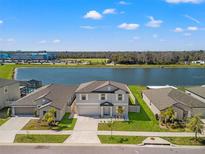 Stunning aerial view of a lakeside home with lush landscaping and a screened pool, creating a serene and private oasis at 11508 Sage Canyon Dr, Riverview, FL 33578