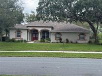 Charming single-story home with mature trees, a well-maintained lawn, and a welcoming double-door entrance at 13133 Roseanna Dr, Spring Hill, FL 34609