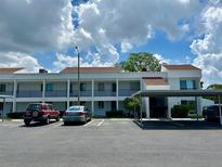 Exterior view of condo building with carport and parking spaces on a sunny day at 2060 Marilyn St # 121, Clearwater, FL 33765