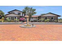 Stunning two-story home featuring brick accents, mature trees, fountain, and a beautiful brick driveway at 2309 Cypress Walk Way, Ruskin, FL 33570