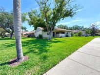 Charming single story home features a lovely front yard with mature trees and manicured lawn at 30 Tads Trl, Oldsmar, FL 34677