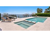 Luxury waterfront pool and dock with lounge chairs offer a perfect outdoor oasis with stunning views at 5110 W Longfellow Ave, Tampa, FL 33629