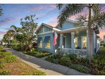 Charming coastal home featuring a manicured lawn, inviting porch, and beautiful landscaping at 610 Winterside Dr, Apollo Beach, FL 33572