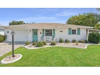 Charming single-story home featuring a well-manicured lawn and a quaint front porch with seating at 708 Rutgers Pl, Sun City Center, FL 33573