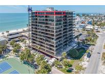 Exterior of a tall condominium building with multiple floors, balconies, ocean view, and tennis courts in front at 7600 Bayshore Dr # 1201A, Treasure Island, FL 33706