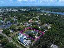 Expansive aerial view of property showcasing lush greenery, a pool, and surrounding landscape near a lake at 10875 131St St, Largo, FL 33774