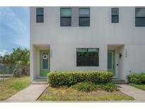 Modern townhome featuring a light-colored exterior, green door with floral wreath, and manicured landscaping at 1330 W Gray St # 1, Tampa, FL 33606