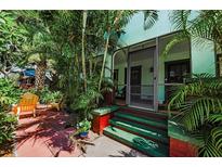 Inviting front porch with colorful accents and lush tropical plants and outdoor chairs at 214 Scotland St, Dunedin, FL 34698