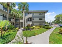 Condo exterior featuring well-maintained landscaping and a walkway to the building entrance at 2650 Countryside Blvd # A210, Clearwater, FL 33761