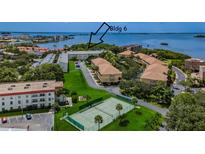Scenic aerial view of condo community with lush landscaping, tennis court, and waterfront access at 2700 Bayshore Blvd # 5210, Dunedin, FL 34698