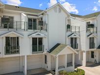 Charming condo featuring a white exterior, dual balconies, and convenient garage access at 320 Island Way # 205, Clearwater Beach, FL 33767