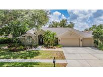 Charming home featuring a three car garage, a well-manicured lawn and lush tropical landscaping at 4320 Auston Way, Palm Harbor, FL 34685