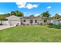 Charming white brick home featuring a lush green lawn, beautiful landscaping, and a welcoming front entrance at 5008 Stolls Ave, Tampa, FL 33615