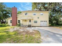 Charming two-story home with a brick chimney, front porch, and a driveway leading to a one-car garage at 6024 90Th N Ave, Pinellas Park, FL 33782