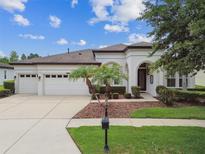 Charming single-story home featuring a three-car garage and well-manicured landscaping with palm trees at 8413 Swiss Chard Cir, Land O Lakes, FL 34637