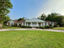 Charming brick home with a manicured lawn, covered porch with columns, and a circular driveway at 1002 W Pinedale Dr, Plant City, FL 33563