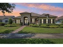 Inviting single-story home with a manicured lawn, stone accents, and a tile roof at sunset at 14715 Fishhawk Preserve Dr, Lithia, FL 33547