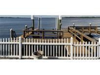 Wooden dock featuring a boat lift and a white picket fence for added safety and charm, with a view of the calm waters at 31 Freshwater Dr, Palm Harbor, FL 34684