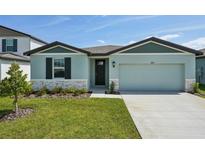 Charming single-Gathering home featuring a two-car garage, manicured lawn, and stone accents at 31647 Malbec Dr, Brooksville, FL 34602