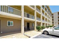 Low angle view of a condo exterior with a private balcony, unit 118, rock ground cover and a white car in the parking lot at 3534 Lake Bayshore Dr # 118, Bradenton, FL 34205