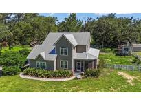 Charming two-story home with a metal roof, a screened-in porch, and a beautiful, well-maintained front yard at 37309 Fountain Rd, Zephyrhills, FL 33542