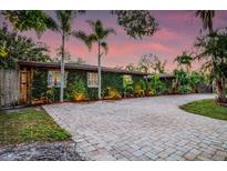 Charming single-story home with lush, green vine-covered facade and paver driveway surrounded by mature landscaping at 4301 S Lockwood Ridge Rd, Sarasota, FL 34231