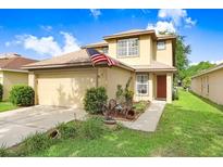 Inviting two-story home featuring a well-manicured lawn, attached garage and patriotic American flag at 5525 Turtle Crossing Loop, Tampa, FL 33625