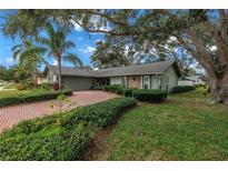 Charming home showcasing mature landscaping, including red brick drive, large trees, and lush green bushes at 9611 107Th N Ave, Largo, FL 33773