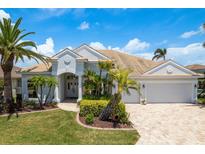 Charming home featuring lush landscaping, a barrel tile roof, and a brick driveway at 987 Chickadee Dr, Venice, FL 34285