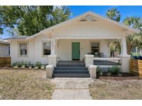 Charming bungalow featuring a teal front door, covered porch and well-maintained landscaping at 1003 E Emma St, Tampa, FL 33603