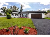 Charming single-story home with a well-maintained lawn, black asphalt driveway, and manicured landscaping at 1873 Murray Ave, Clearwater, FL 33755