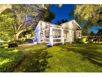 Charming home featuring a welcoming front porch, lush lawn, and mature trees illuminated at night at 213 N Hesperides St, Tampa, FL 33609
