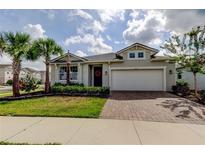 Charming single-Gathering home with a well-manicured lawn, palm trees, and a brick driveway at 2456 Arbor Wind Dr, Lutz, FL 33558