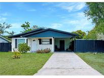 Charming single-story home with a well-manicured lawn, and a carport with chairs at 2606 E 97Th Ave, Tampa, FL 33612