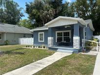 Charming blue bungalow featuring a welcoming front porch with stone accents and a well-manicured lawn at 3718 N 36Th St, Tampa, FL 33610