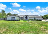 Inviting one-story home with a lush green lawn, mature landscaping, and a screened front entrance at 6219 Wendell Dr, Wesley Chapel, FL 33544