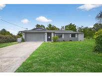 Charming one-story home featuring a well-manicured lawn and a gray painted exterior at 6310 Gainsboro Ave, Spring Hill, FL 34609