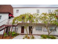 Condo building with white facade, dark trim, exterior stairs, and landscaping at 9217 Tudor Dr # A106, Tampa, FL 33615