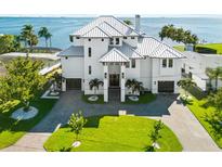 View of waterfront property featuring a white exterior, manicured lawn, and metal roof at 110 Carlyle Dr, Palm Harbor, FL 34683