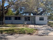 Exterior view of a single-story home with a chain-link fence and mature trees in the front yard at 1716 Lancelot Loop, Tampa, FL 33619