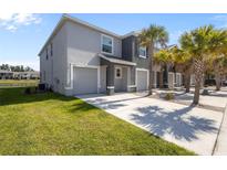 Modern townhome featuring an attached garage, a well-manicured lawn and swaying palm trees at 3334 Pleasant Willow Ct, Brandon, FL 33511