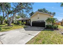 Charming home featuring a well-maintained lawn, mature trees, and an attached garage at 7461 Pescador Pl, Seminole, FL 33772