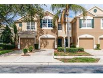 Inviting townhome featuring a well-manicured lawn, two-car garage, and lush landscaping at 8568 Sandy Beach St, Tampa, FL 33634