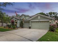 Charming single-Gathering home with a three-car garage, green lawn, and colorful landscaping at 10709 Rockledge View Dr, Riverview, FL 33579