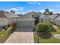 Beautiful single-story home featuring a brick driveway, attached garage, and tropical landscaping at 1110 Jasmine Creek Ct, Sun City Center, FL 33573