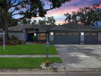 Charming single-story home with a well-maintained lawn and mature trees, plus a three car garage and colorful sunset at 120 Fernbrook Rd, Oldsmar, FL 34677