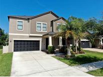 Charming two-story home featuring a dark garage door, landscaped yard, and inviting front porch at 13903 Sage Thrasher Ln, Riverview, FL 33579